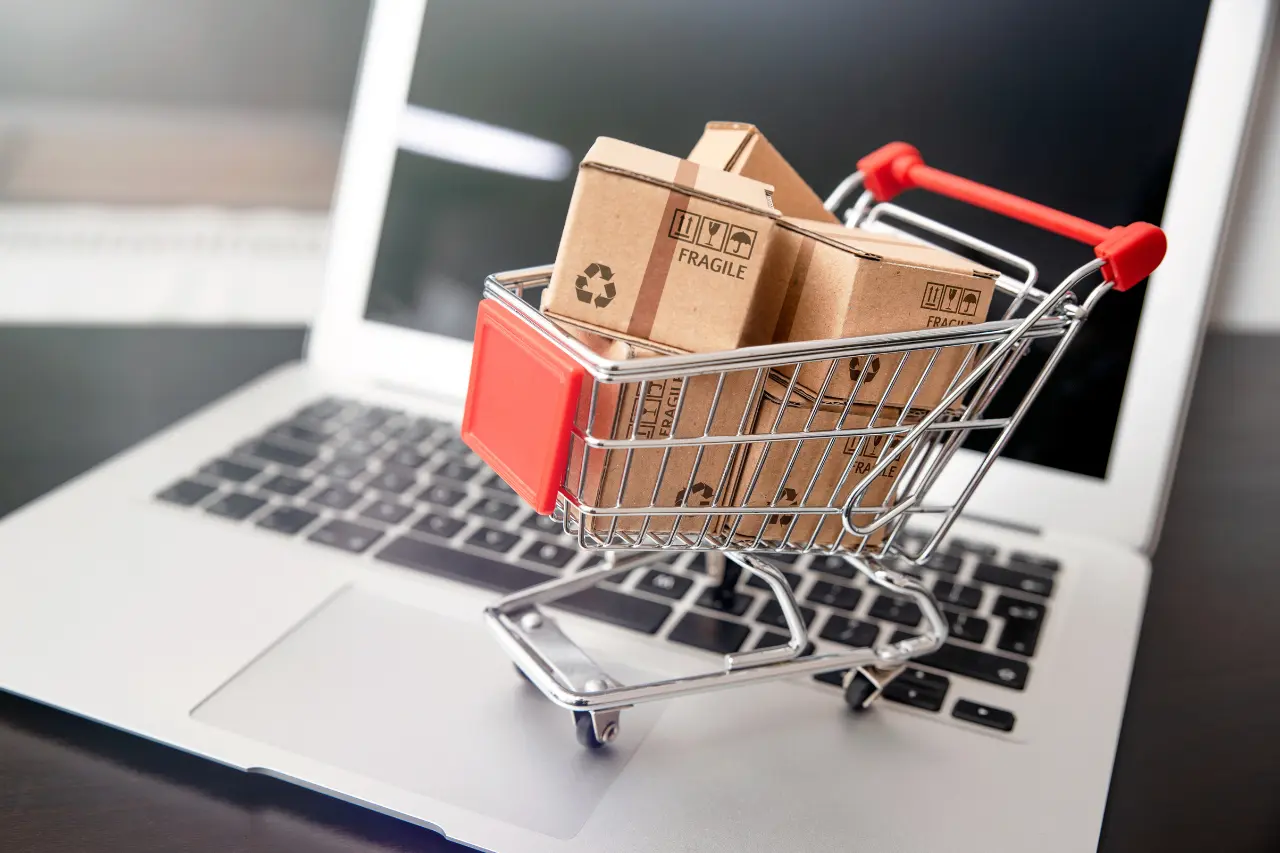 Miniaturowy wózek z paczkami na klawiaturze laptopa – symbol sprzedaży w e-commerce