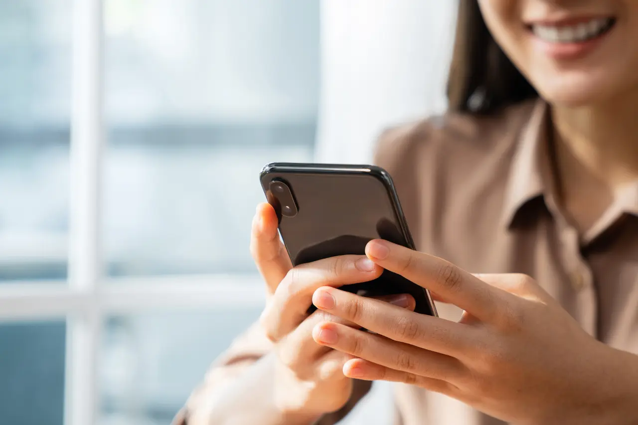Uśmiechnięta kobieta korzystająca ze smartfona