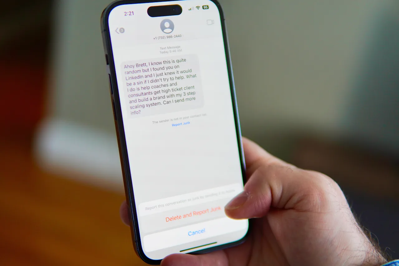 Smartfon z podejrzaną wiadomością SMS od nieznanego nadawcy i opcją zgłoszenia jej jako spam